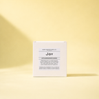 A white box labeled 'Joy' standing upright on a pale yellow background.