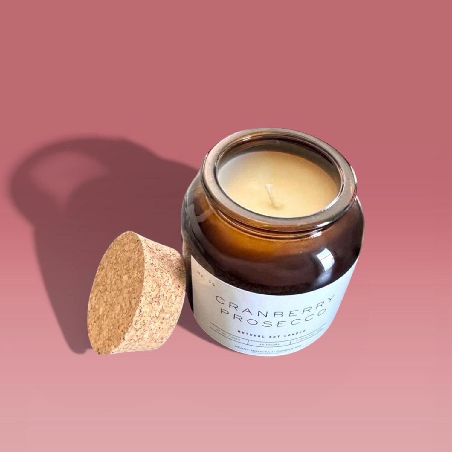 prosecco fragrance soy wax candle with sparkling cranberry scent in amber apothecary jar with cork lid non-toxic clean burn candle for cozy living room or bedroom decor gift for her self care candle handmade long burn time