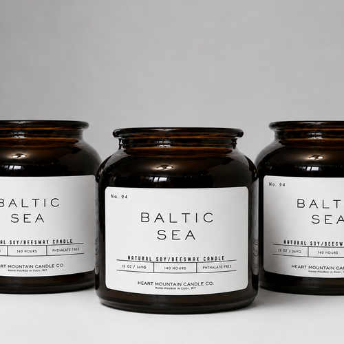 Three amber glass Baltic Sea candles on a gray background.
