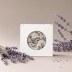 A boxed Unwind bath bomb styled with fresh lavender sprigs on a tan background.