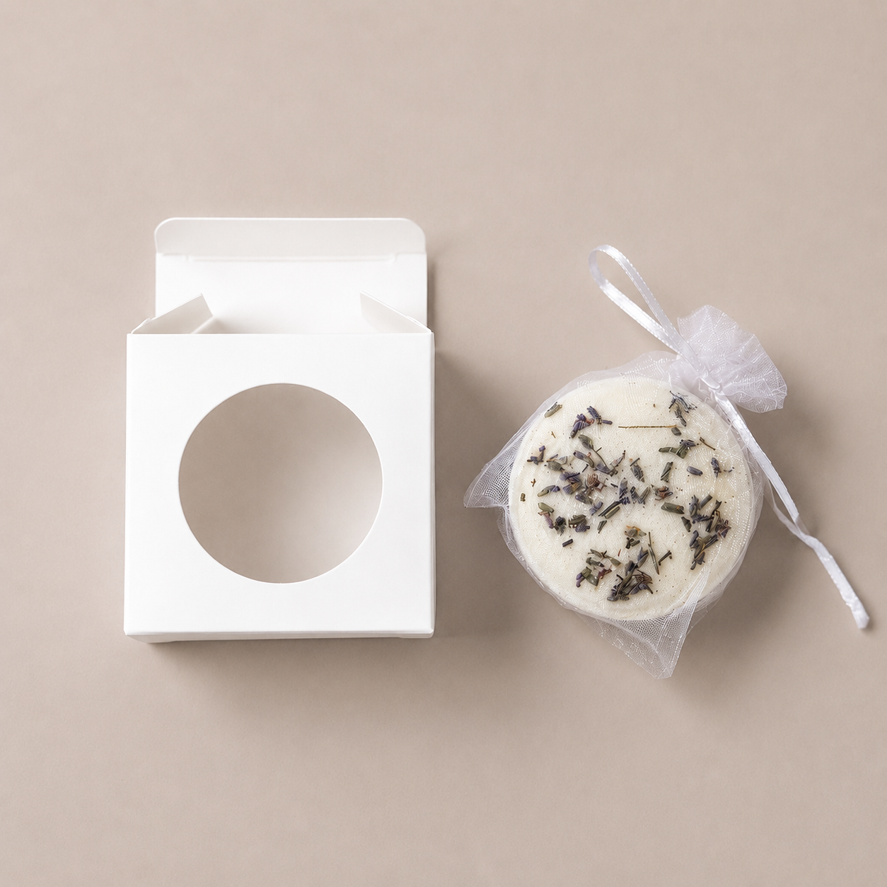 Open white gift box with circular window next to a round Unwind bath bomb wrapped in mesh and ribbon.