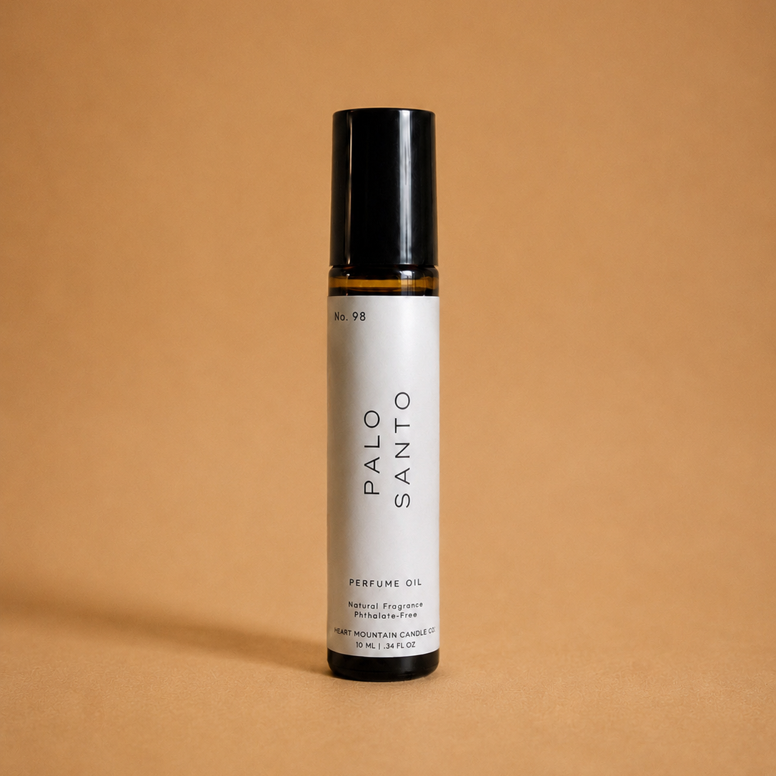 A Palo Santo perfume oil rollerball bottle on a tan background.