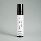 A Himalayan Orchid perfume oil rollerball bottle on a light gray background.