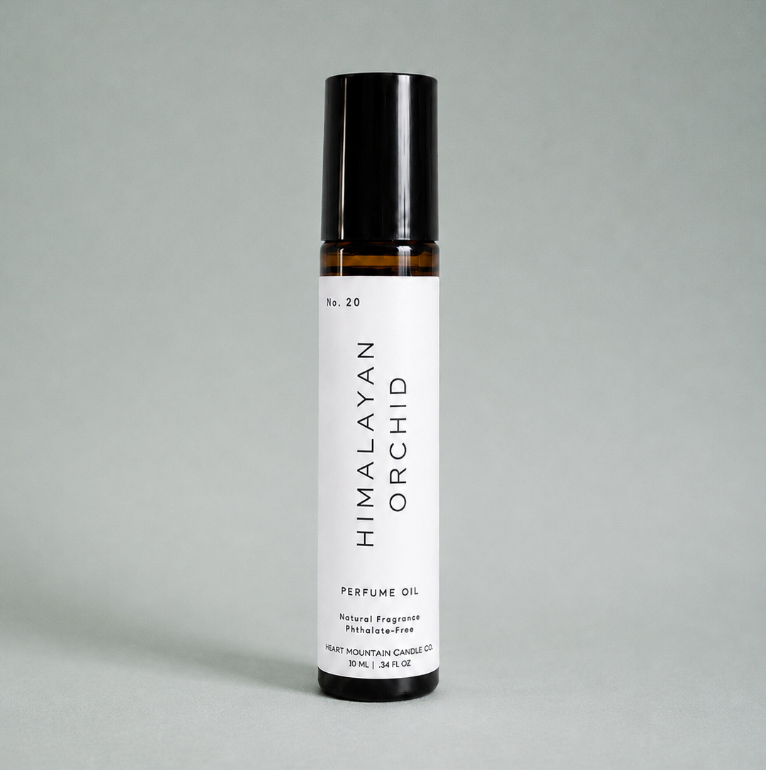A Himalayan Orchid perfume oil rollerball bottle on a light gray background.