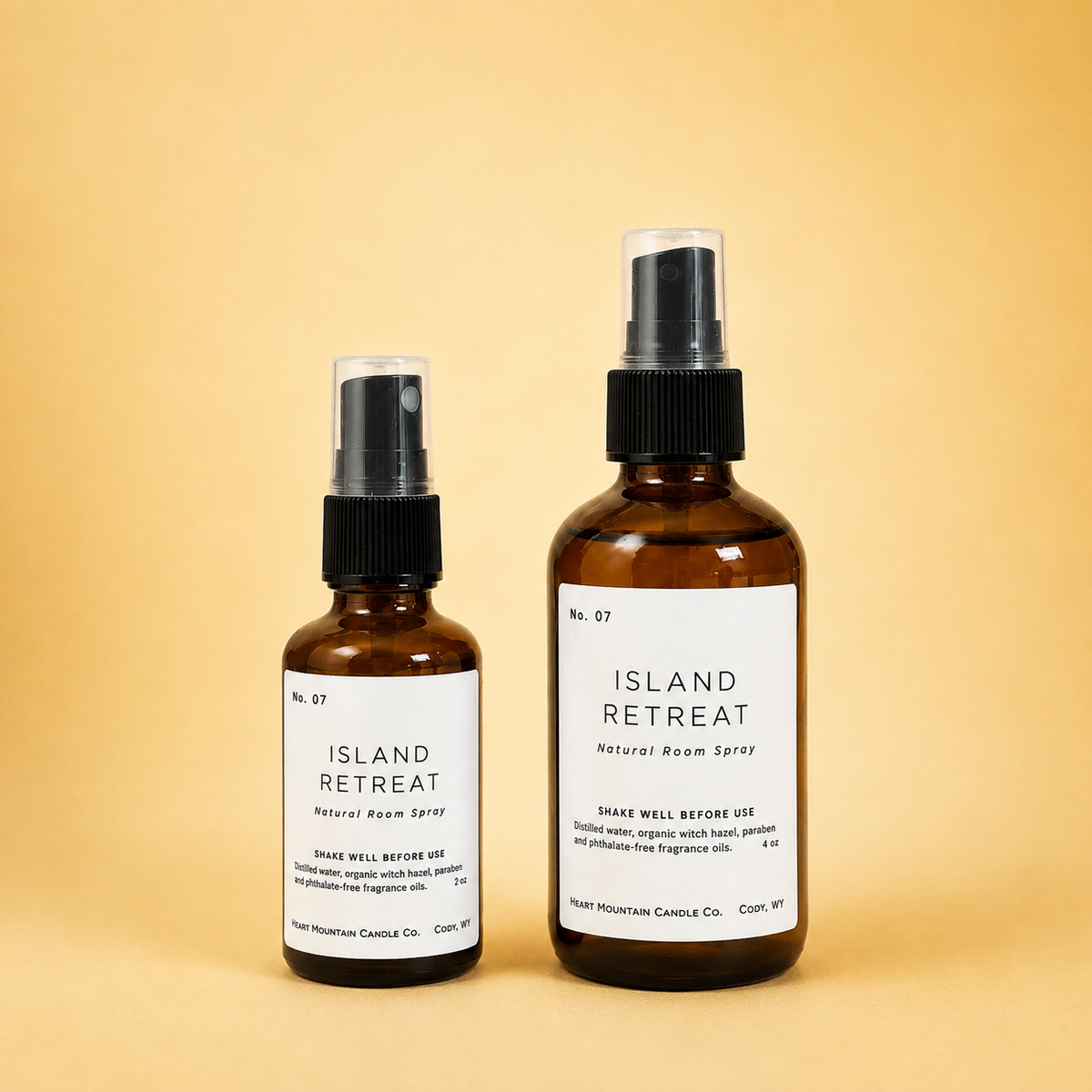 Two Island Retreat room spray bottles in different sizes on a yellow background.