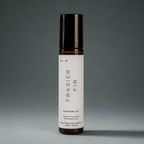 Amber glass Frasier Fir rollerball perfume oil with a black cap on a gray background.
