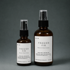Two amber glass Frasier Fir room spray bottles, small and large sizes, on a gray background.