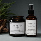Amber glass Frasier Fir candle and room spray bottle with pine branches on a gray background.