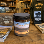 Yellowstone candle in amber glass jar styled in rustic national park inspired setting with earthy woods fresh trees dirt and mountain air fragrance cozy cabin decor candle for Yellowstone lovers Wyoming souvenir gift national park gift Christmas gift birthday gift Father’s Day gift housewarming gift anniversary gift gift for him gift for her outdoorsy gift for campers hikers travelers and adventure lovers clean-burning soy and beeswax candle with rugged wilderness inspired atmosphere